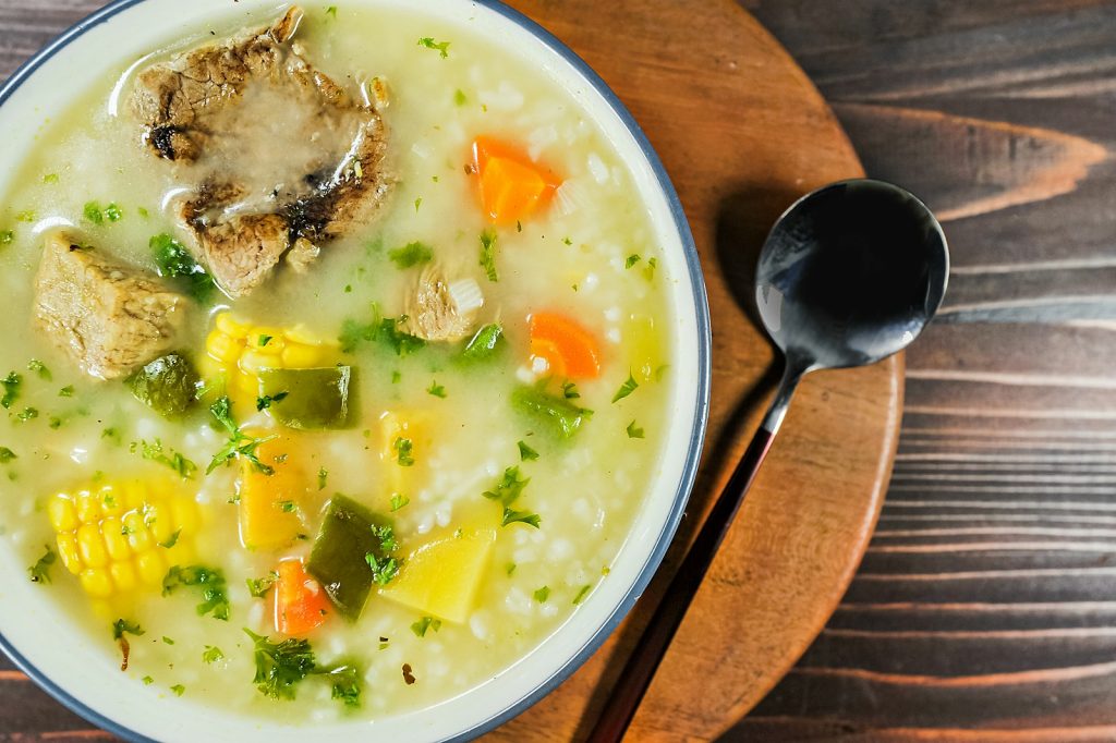 Une soupe de poulet aux légumes dans une assiette creuse.